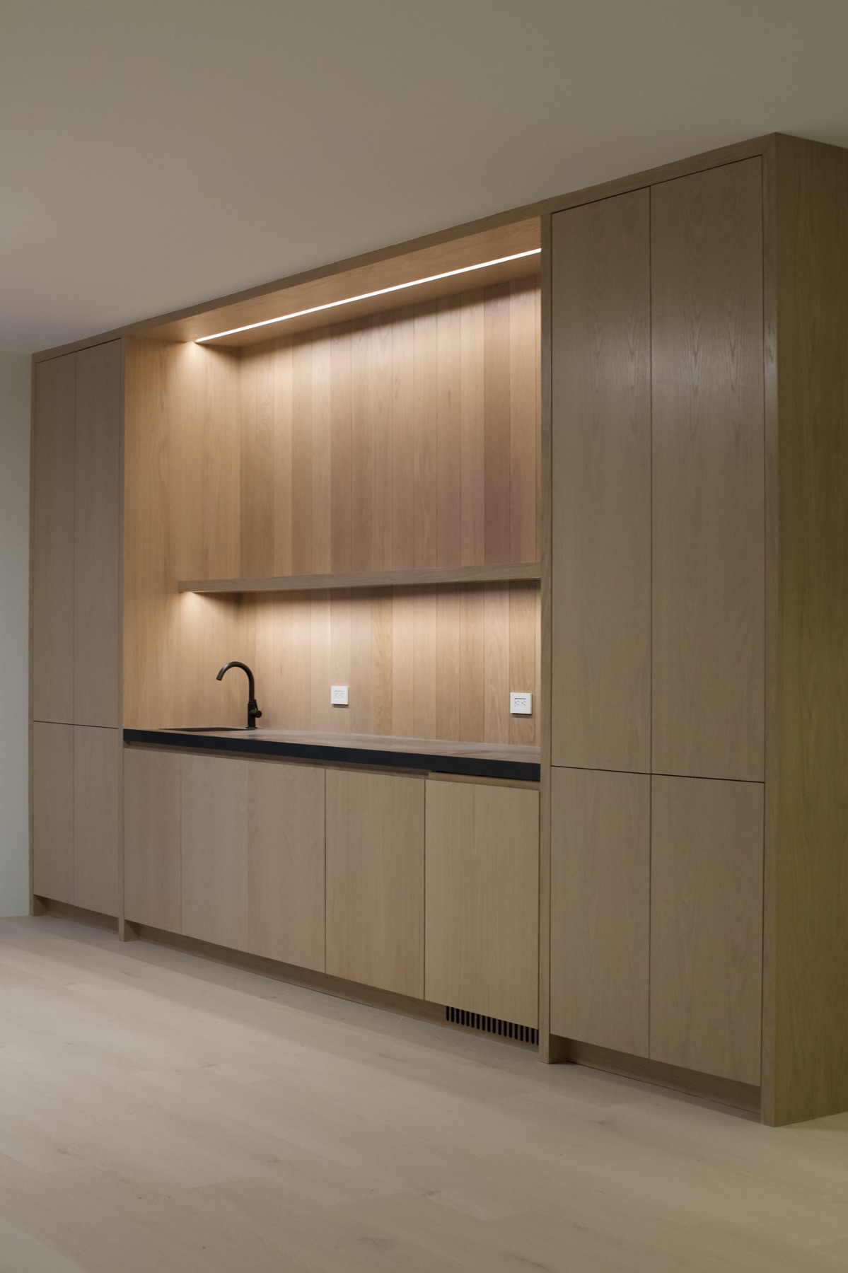 Custom white oak bar with integrated lighting and stone counter